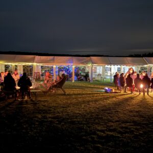 Camperinnen und Camper sitzen am Lagerfeuer auf dem Camp'n'Connect-Treffen