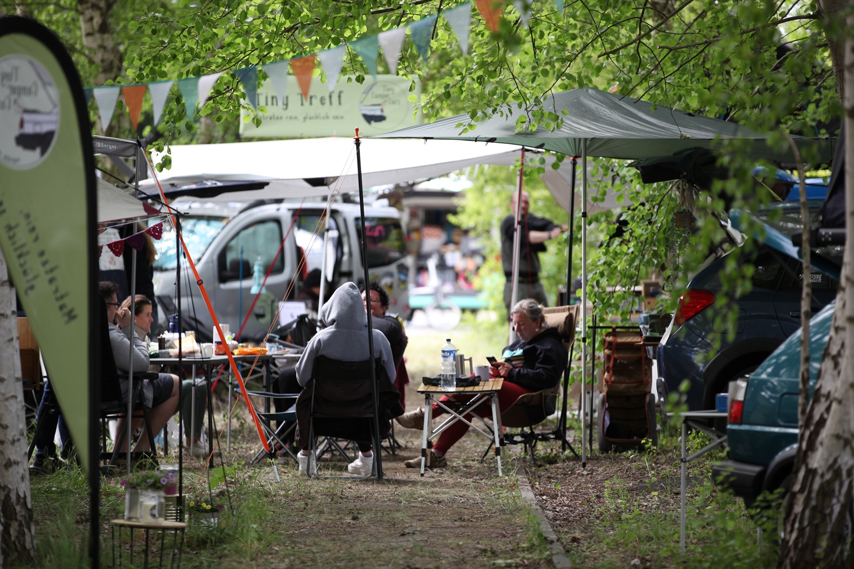 Tiny Camper sitzen im Grünen, trinken Kaffee und unterhalten sich.