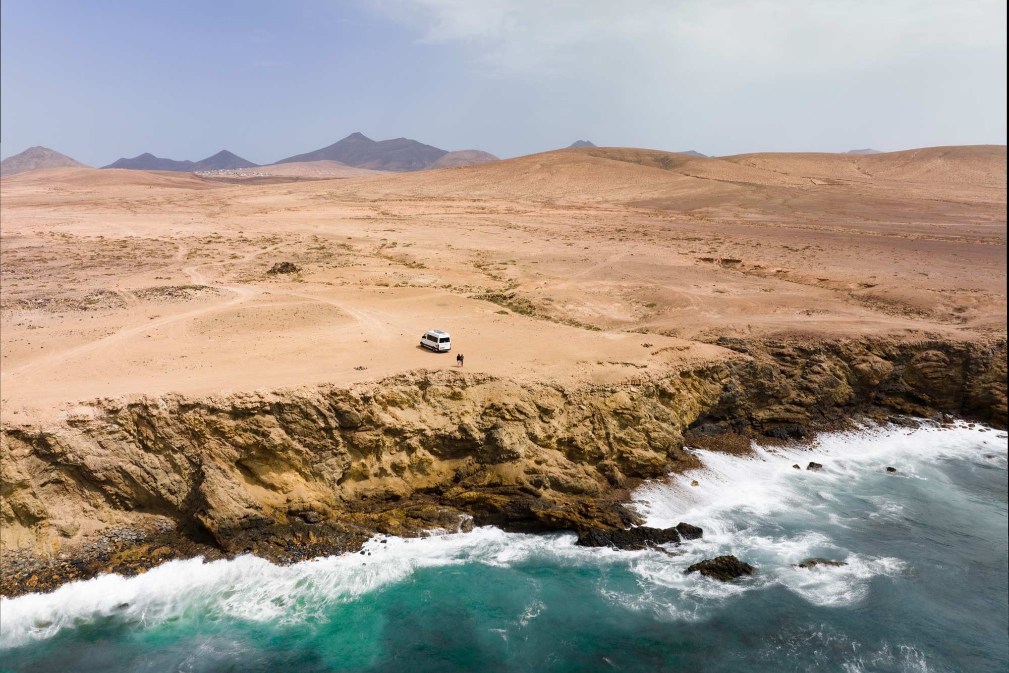 Campervan an einer Steilküste am Meer mit zwei Leuten